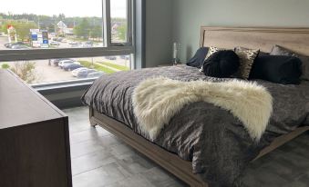 a modern bedroom with a large bed , black and white fur blanket , and a window view at My Place
