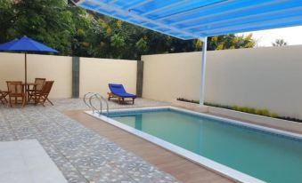 a swimming pool with a blue canopy and lounge chair under it , surrounded by a white fence at Villa Orlando