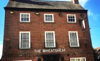 "a red brick building with the sign "" the wheatsheaf "" on it , under a clear blue sky" at The Wheatsheaf Pub, Kitchen & Rooms