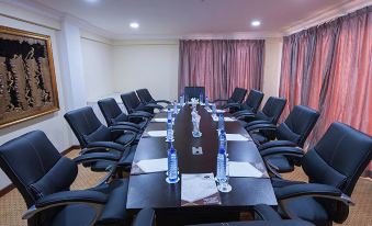 a conference room with a long table , multiple chairs , and water bottles on the table at Golden Bean Hotel