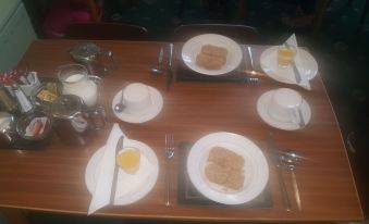 a dining table set with a variety of plates , cups , and utensils , ready for a meal at Gracelands Guest House