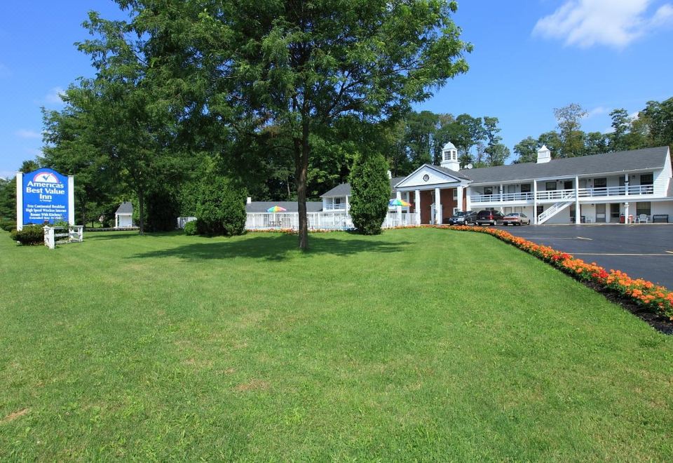 a large , well - maintained yard with a green lawn and a brick house in the background at Colony Motel Jamestown