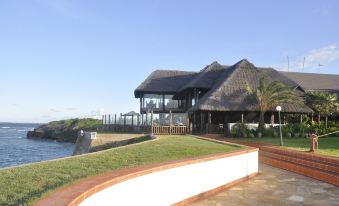 a large building with a thatched roof and a grassy lawn in front of it at Sea Cliff Hotel