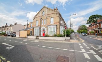 a brick building with a red door on the corner of a street , surrounded by other buildings at Diamonds Villa Near York Hospital