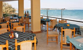 a large dining area with tables and chairs , all set up for a meal , overlooking the ocean at Hotel Bijou