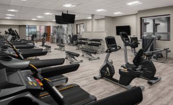 a well - equipped gym with various exercise equipment , including treadmills , stationary bikes , and weight machines , as well as a television at Cleveland Marriott East