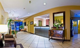 a modern office interior with yellow walls , white floor tiles , and large windows , featuring a reception desk and green plants at Best Western Cowichan Valley Inn