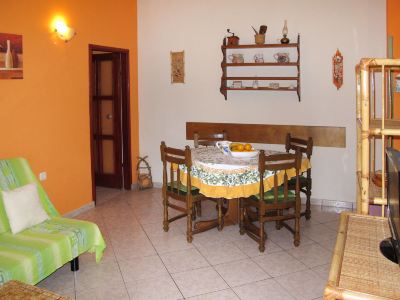 a dining room with a wooden table , chairs , and a couch in front of an orange wall at Ingrid