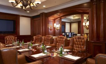 a conference room with a long table and chairs , surrounded by wooden paneling and chandeliers at Palazzo Hotel