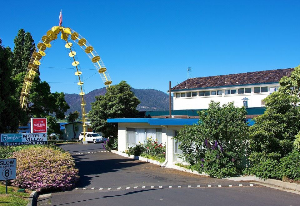 a blue and white house with a large yellow umbrella in front of it , surrounded by trees and grass at Riverfront Motel & Villas