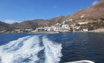 a boat is sailing in the ocean with a mountainous background and houses on it at Apollo Studios