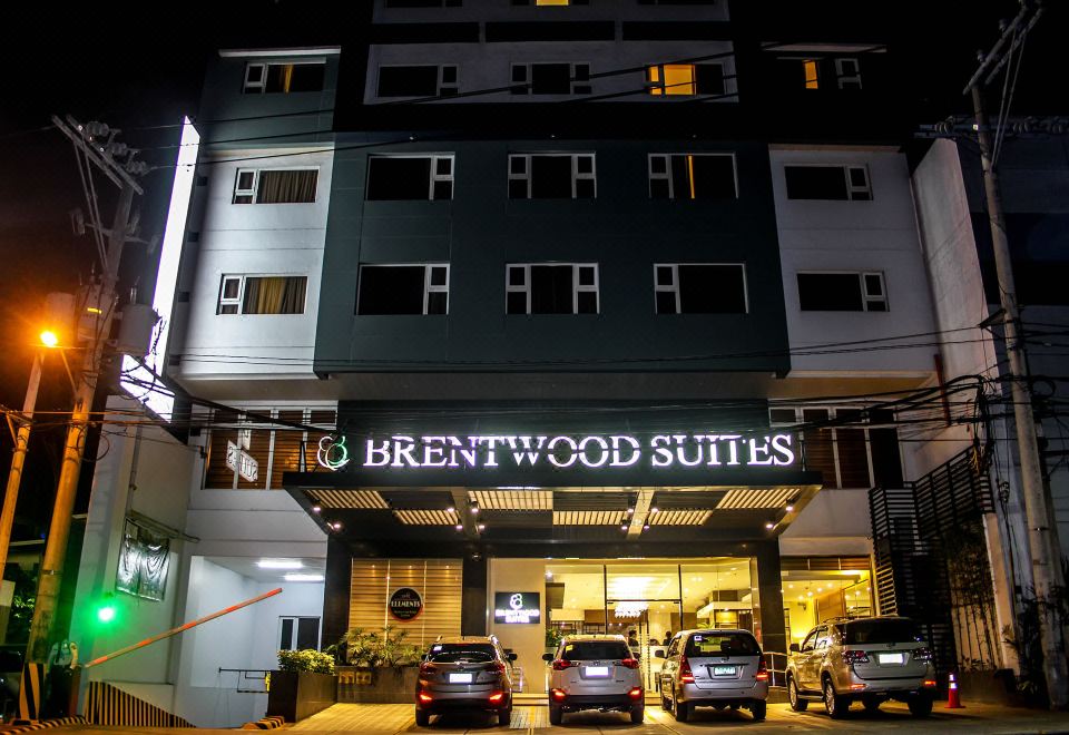 the entrance of the brentwood suites , a hotel with three cars parked in front of it at Brentwood Suites