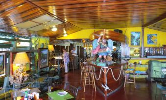 a restaurant with a boat - themed interior and wooden ceiling , where several people are enjoying their meal at Hotel la Mansion Inn Arenal