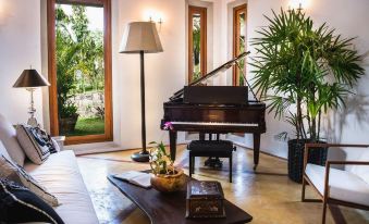 a living room with a large piano in the center , surrounded by chairs and a couch at Eraeliya Villas & Gardens