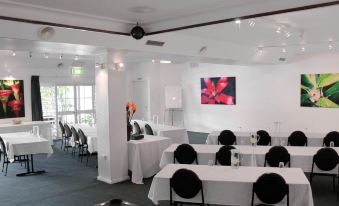 a conference room with tables and chairs , a large screen on the wall , and a potted plant at Motel Nomad