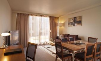 a dining room with a table and chairs , as well as a living room with a couch , chair , and television at Quest Cheltenham