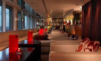 The room is illuminated by overhead lighting and contains tables, chairs, and couches in the center at Royal Garden Hotel
