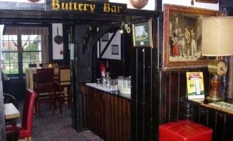 "a pub with a wooden bar and red chairs , featuring a sign that says "" buttery bar .""." at The Royal Hotel