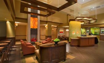 a hotel lobby with a wooden reception desk , comfortable seating area , and a painting on the wall at Hyatt Place Saratoga Malta