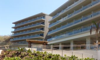 a modern building with multiple balconies and a green walkway leading up to the entrance at Wyndham Tamarindo