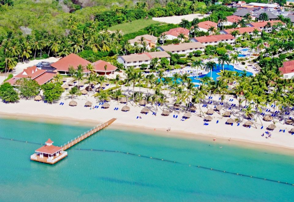 aerial view of a tropical resort with multiple buildings , pools , and sandy beach on the shore at Bahia Principe Grand la Romana - All Inclusive