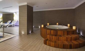a modern , minimalist bathroom with wooden steps leading to a large circular bathtub surrounded by candles at DoubleTree by Hilton Istanbul-Avcilar