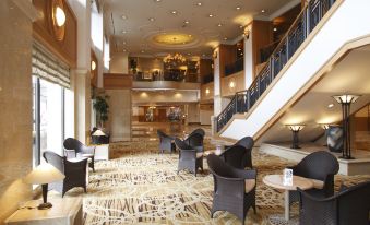 a spacious , well - lit lobby with multiple levels and black leather chairs arranged around tables , providing a comfortable seating area for guests at Noboribetsu Grand Hotel