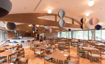 a large dining room with wooden tables and chairs , a bar in the background , and hanging decorations at Karuizawa Prince Hotel East