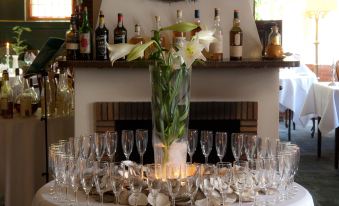 a vase with white flowers is displayed on a table surrounded by multiple wine glasses at Hotel Dagmar