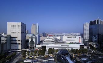 a city skyline with tall buildings and numerous cars on the road , set against a clear blue sky at Kawasaki Nikko Hotel
