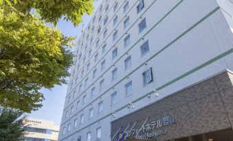 a modern building with a white exterior and large windows , surrounded by trees and a clear blue sky at Comfort Hotel Koriyama