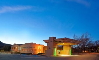 a modern building with a green roof and yellow accents is lit up at night at Holiday Inn Canyon de Chelly (Chinle)