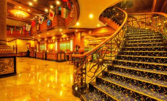 a grand staircase with a blue and gold carpeted floor leads up to the second floor of a hotel at Planet Holiday Hotel & Residence