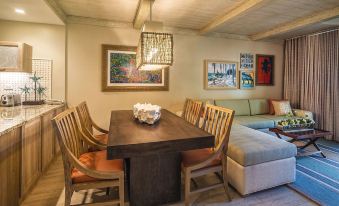 a dining room with a wooden table surrounded by chairs , and a couch in the background at Margaritaville Vacation Club by Wyndham - St Thomas