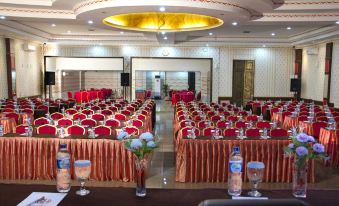 a large conference room set up for a meeting , with multiple tables and chairs arranged in rows at Griya Hotel
