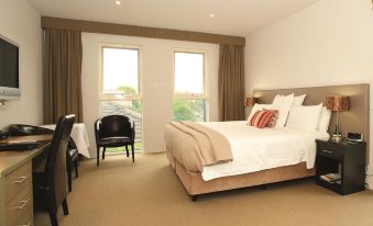 a large bed with white linens and a brown headboard is in a room with a window at Brooklands of Mornington