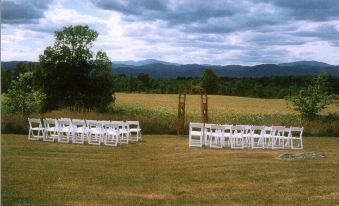 a wedding ceremony is taking place in a field , with chairs arranged for guests at Whitford House