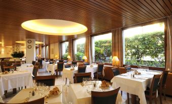 a large dining room filled with tables and chairs , where several people are enjoying a meal at Hotel Majestic