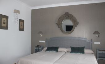 a bedroom with a large bed , a mirror on the wall , and two lamps hanging from the ceiling at Hotel Villa Maria