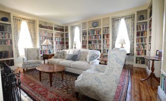 a spacious living room with a large couch , chairs , and a bookshelf filled with books at Woodville Bed and Breakfast