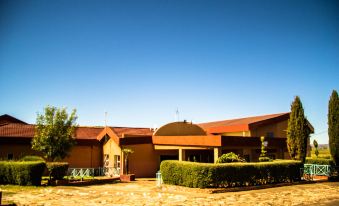 a large building with a red roof and brown walls is surrounded by a well - maintained courtyard at The Palace Hotel