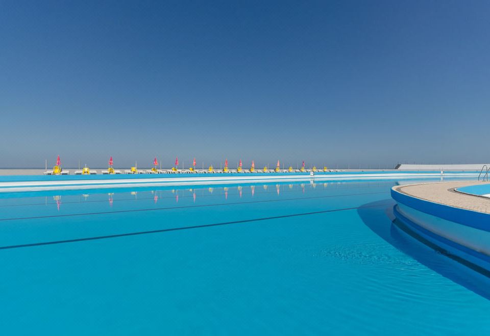 a large blue pool with red and yellow rafts on the water , surrounded by a fence at Arribas Sintra Hotel