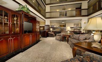 a spacious living room with high ceilings , a large flat - screen tv mounted on the wall , and a dining table at Drury Inn & Suites St. Louis Airport
