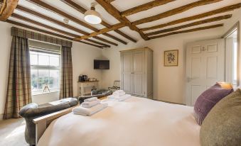 a large bed with white linens is in a room with a wooden ceiling and a television at The Rodney