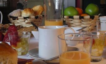 a table is set with a pitcher , cups of orange juice , bread , and fruit in a basket at Punto y Aparte
