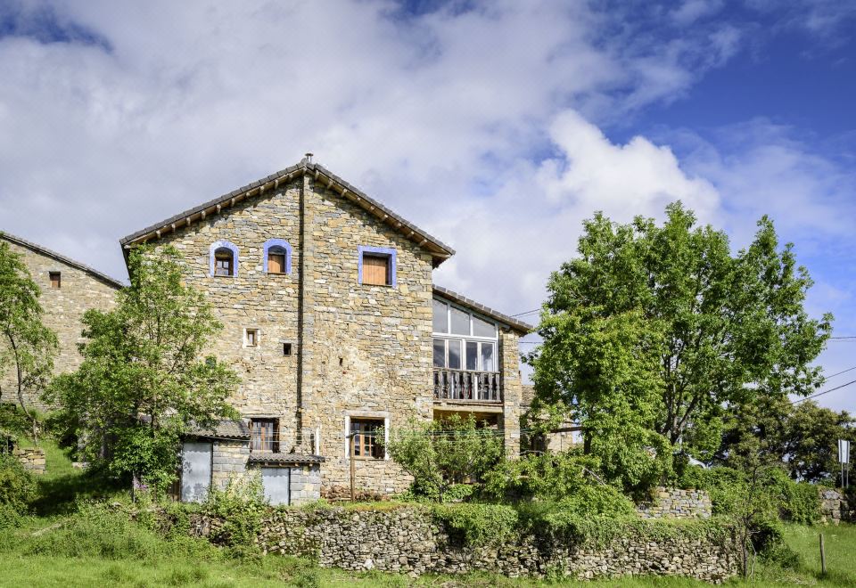 a stone building with a large window and balconies is surrounded by trees and grass at Casa Marina