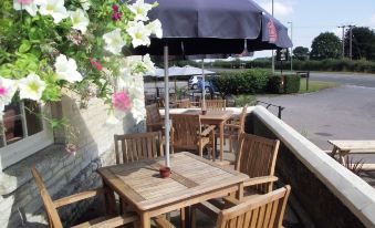 a wooden dining table and chairs set up in a restaurant patio area , with an umbrella providing shade at Sturdys Castle