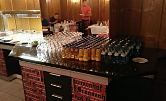 a well - stocked bar with numerous bottles and glasses , as well as a dining table filled with wine glasses at Hotel Brunnenhof