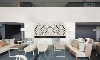 a modern living room with white furniture , including a couch , chairs , and a coffee table at NH Parma