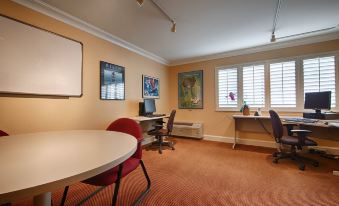 a room with a round table , two chairs , and a computer desk is shown with beige walls and orange carpet at Best Western Plus Novato Oaks Inn